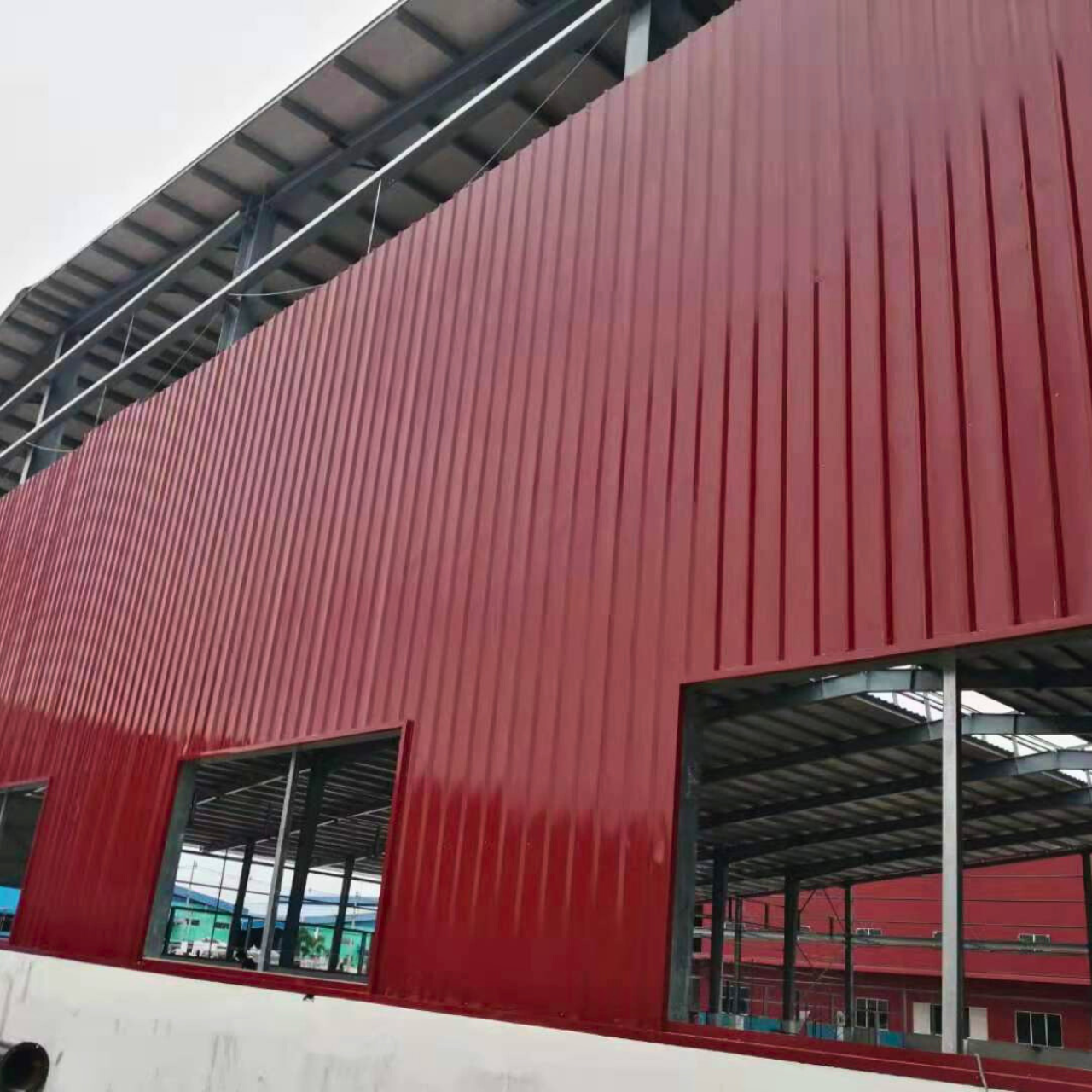 Myanmar Yi Jin is installing red exterior wall cladding on a steel structure warehouse at their project site in Yangon, Myanmar, highlighting the building's facade.