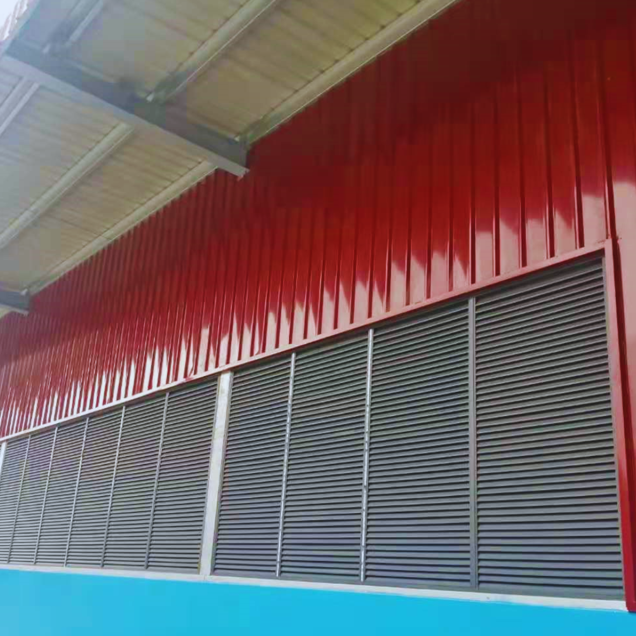 Exterior view of the finished red wall cladding and grey ventilation louvres on a Myanmar Yi Jin steel structure warehouse project site in Yangon, Myanmar.