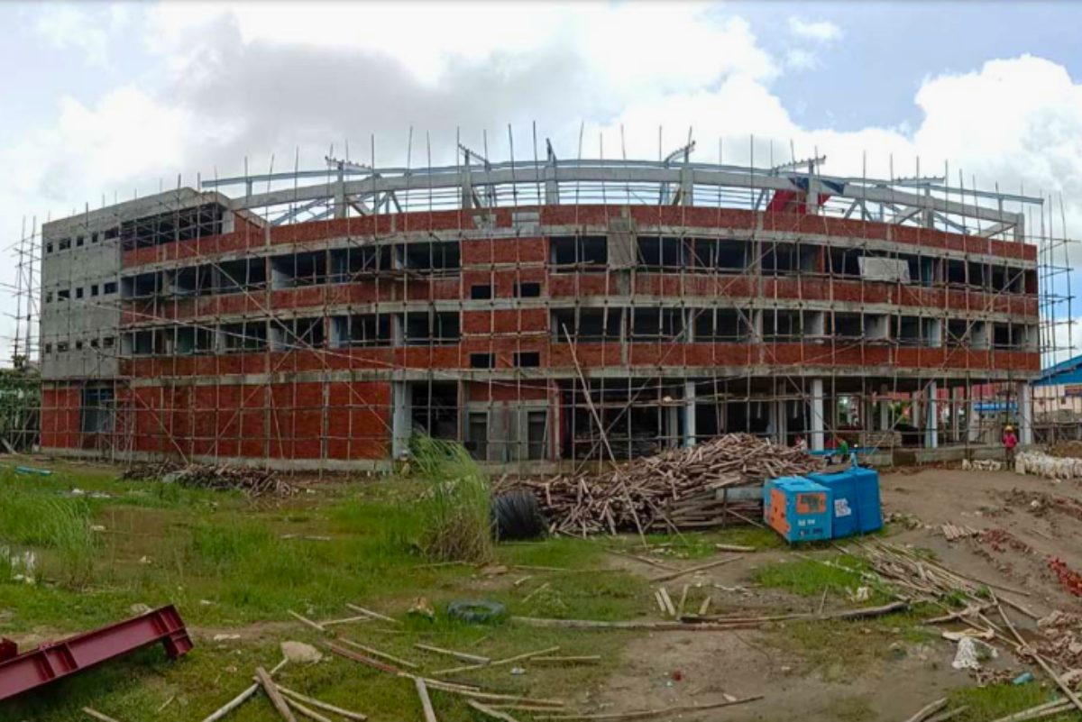 Progress photo of the Myanmar Panda Manufacturing Company Limited 4-storey RCC building under construction by Myanmar Yi Jin, showing scaffolding, brickwork, and structural framing.